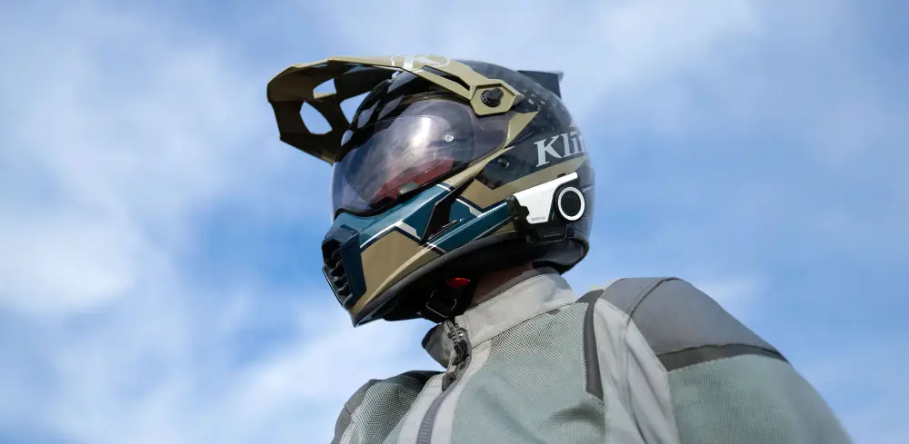 Low angle shot of a rider wearing a Klim adventure helmet fitted with the sena 60s Bluetooth motorcycle helmet headset, against a blue sky.
