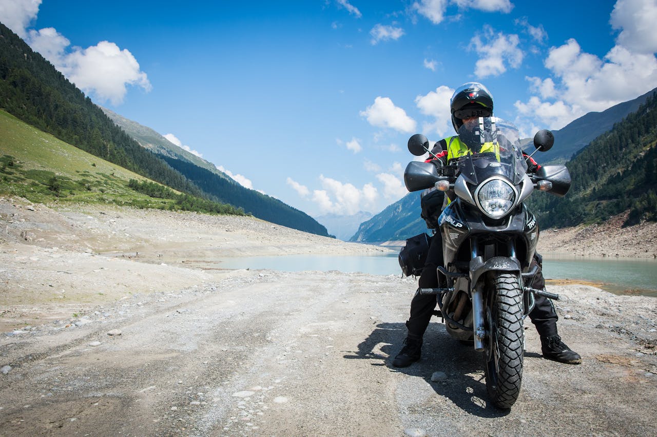 Motorcyclist on a road trip by a mountain lake, representing adventure and exploration.