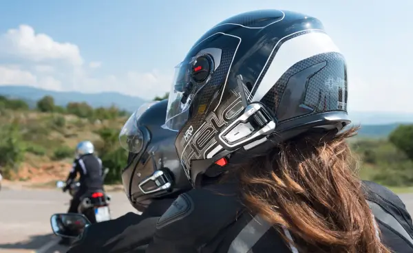 Stay-Connected-on-the-Road-with-a-Bluetooth-5-3-Motorcycle-Headset A close-up shot from behind two motorcyclists, a driver and a passenger, on a scenic road. Both riders are wearing helmets equipped with a sleek bluetooth 5.3 motorcycle headset for clear communication on their journey.